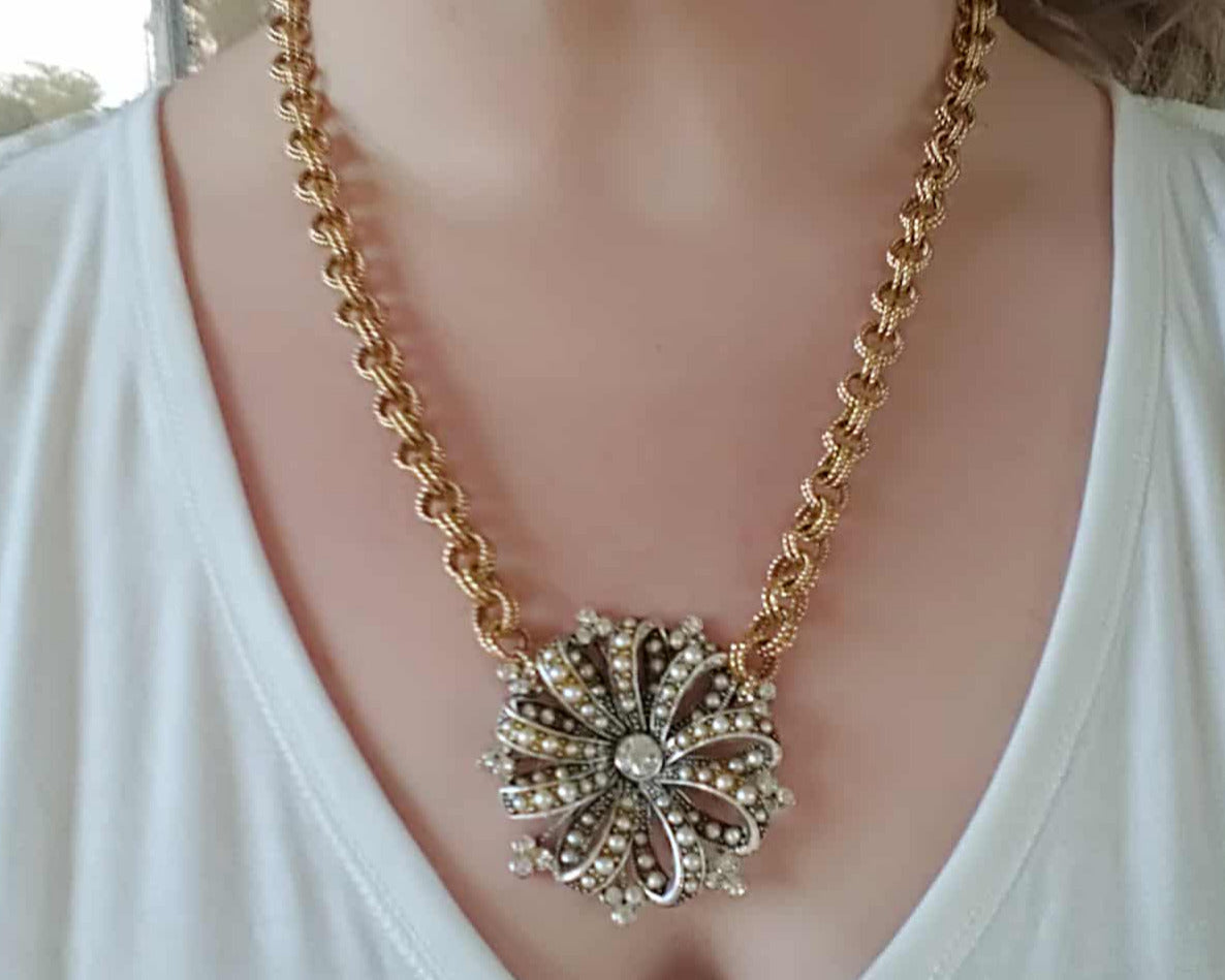 Gold chain necklace with a decorative pendant on a white background