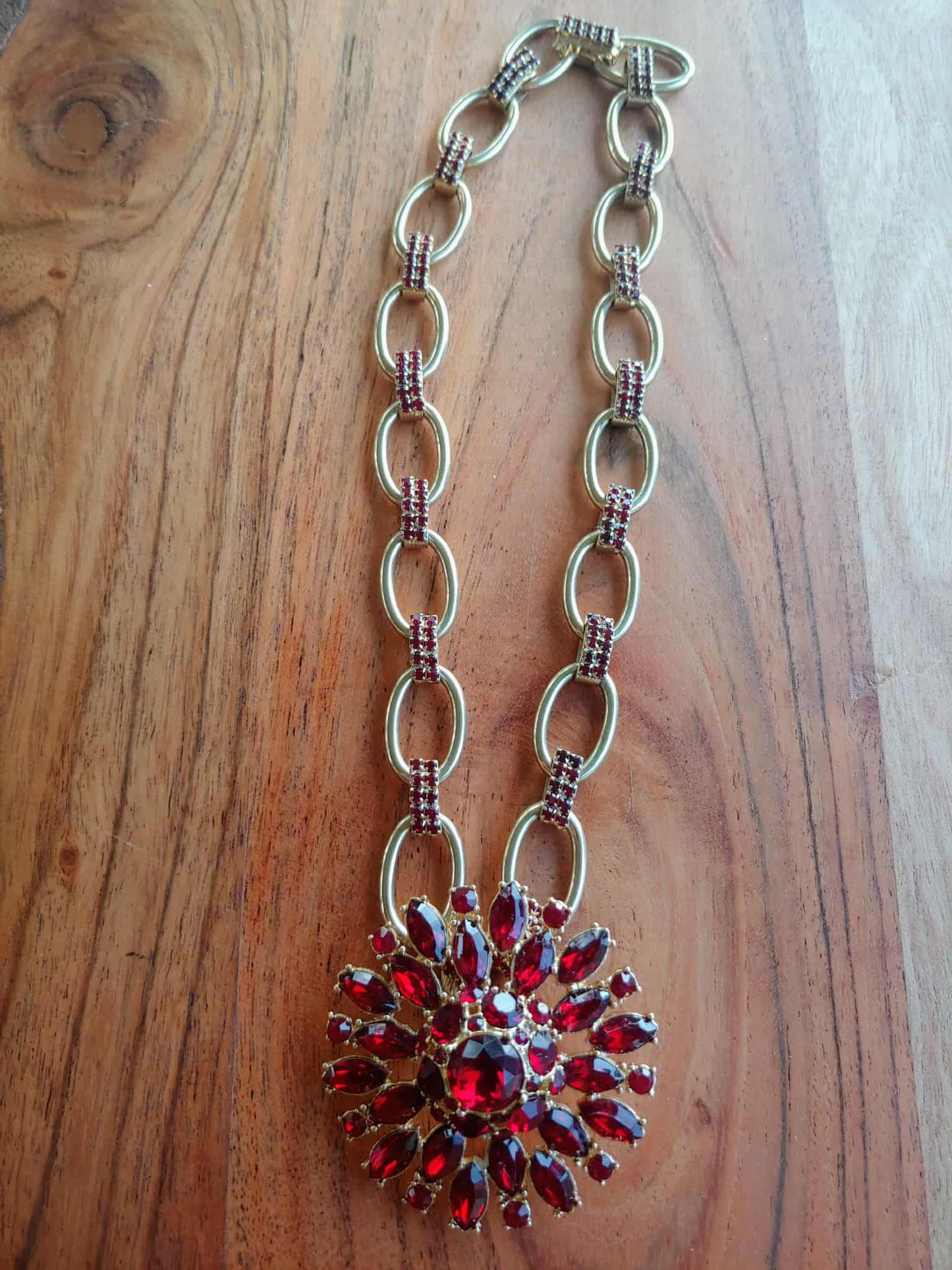 necklace with red gemstone pendant on a wooden surface