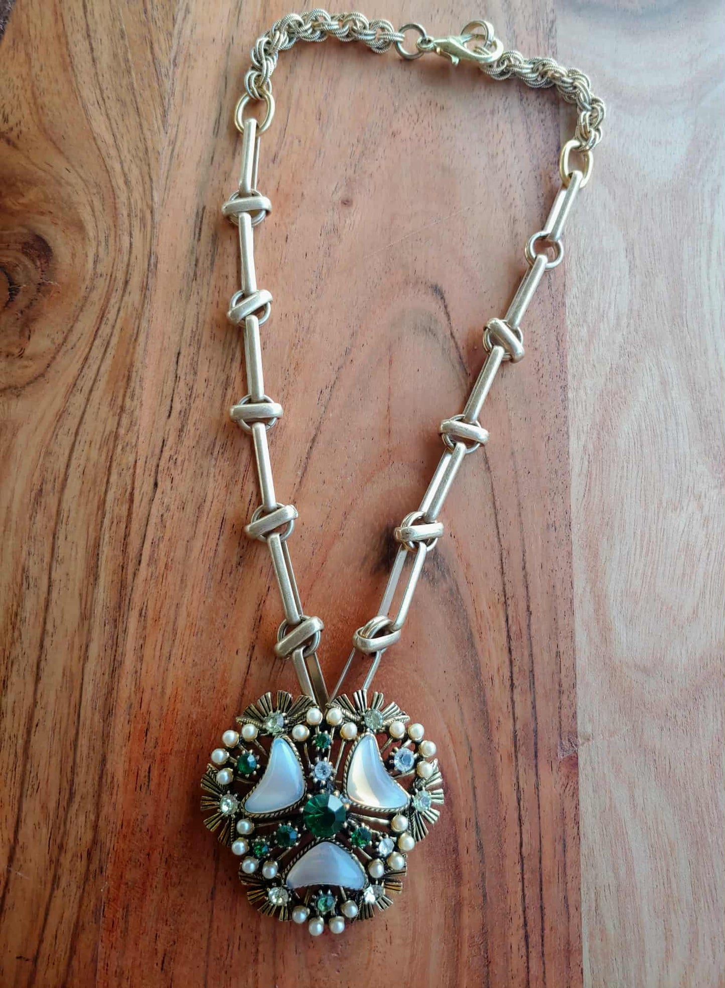 Silver necklace with a detailed pendant on a wooden surface