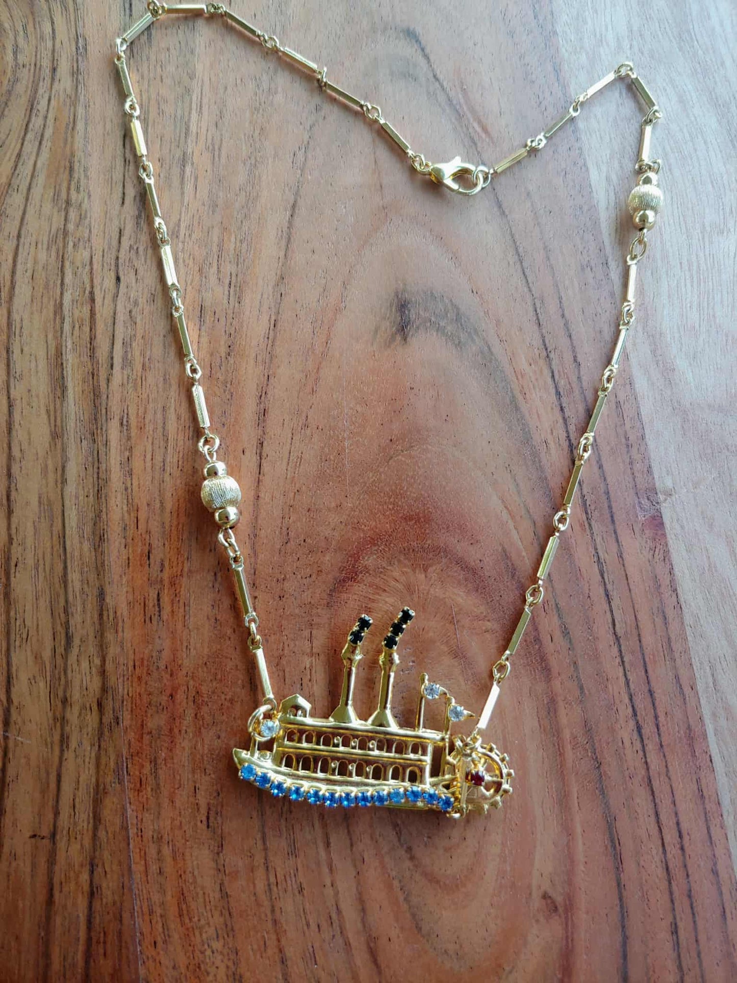 Gold necklace with a detailed pendant on a wooden surface