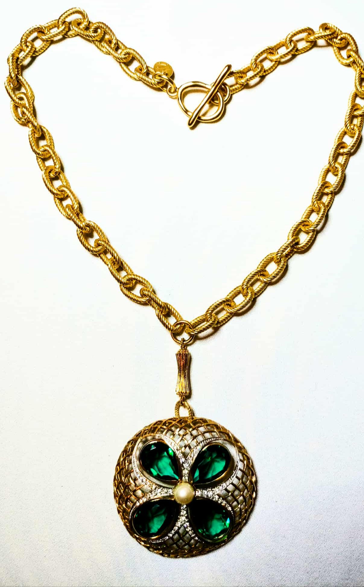 Gold necklace with a green pendant on a white background