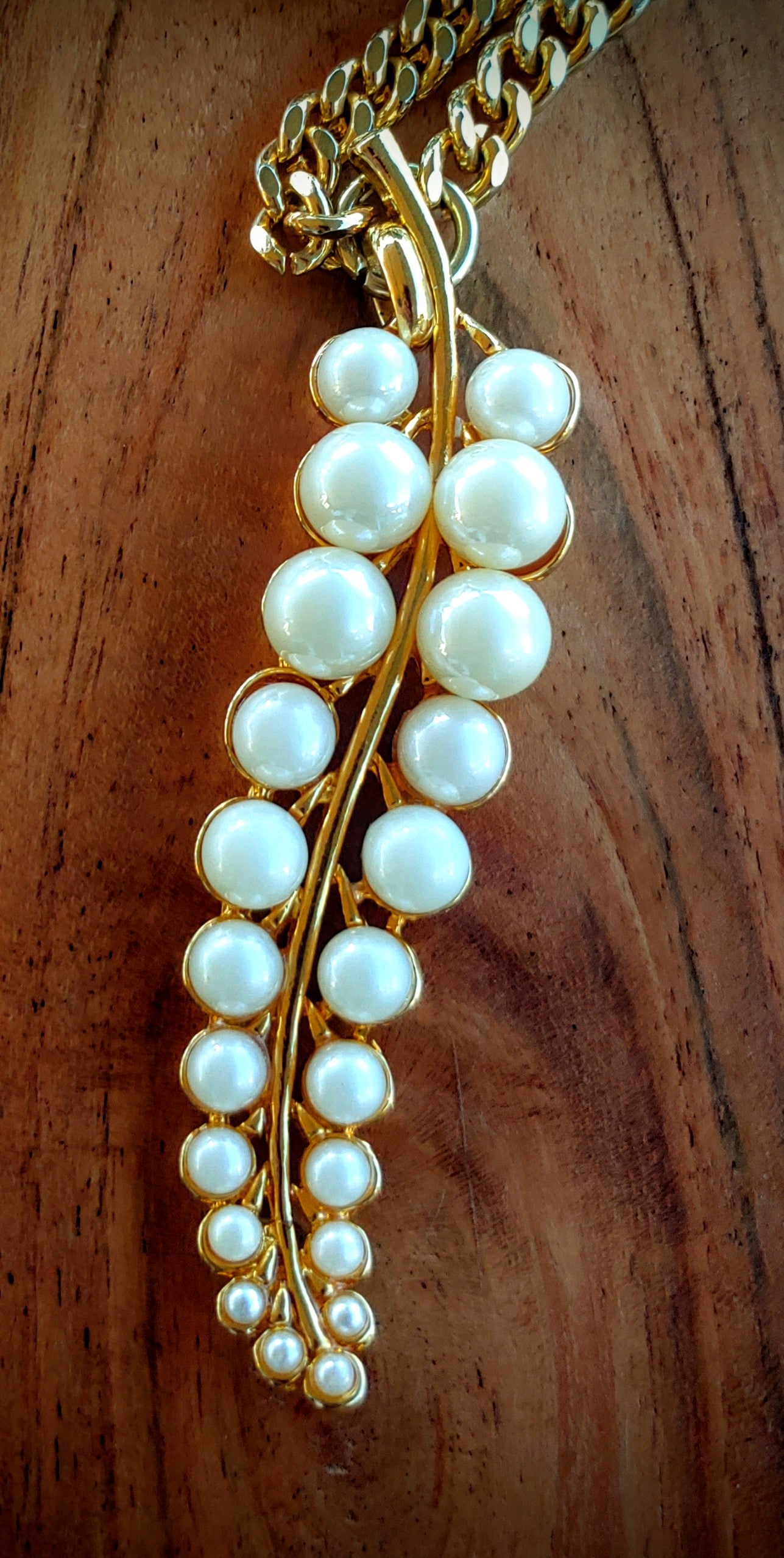 Pearl necklace with gold chain on a wooden surface