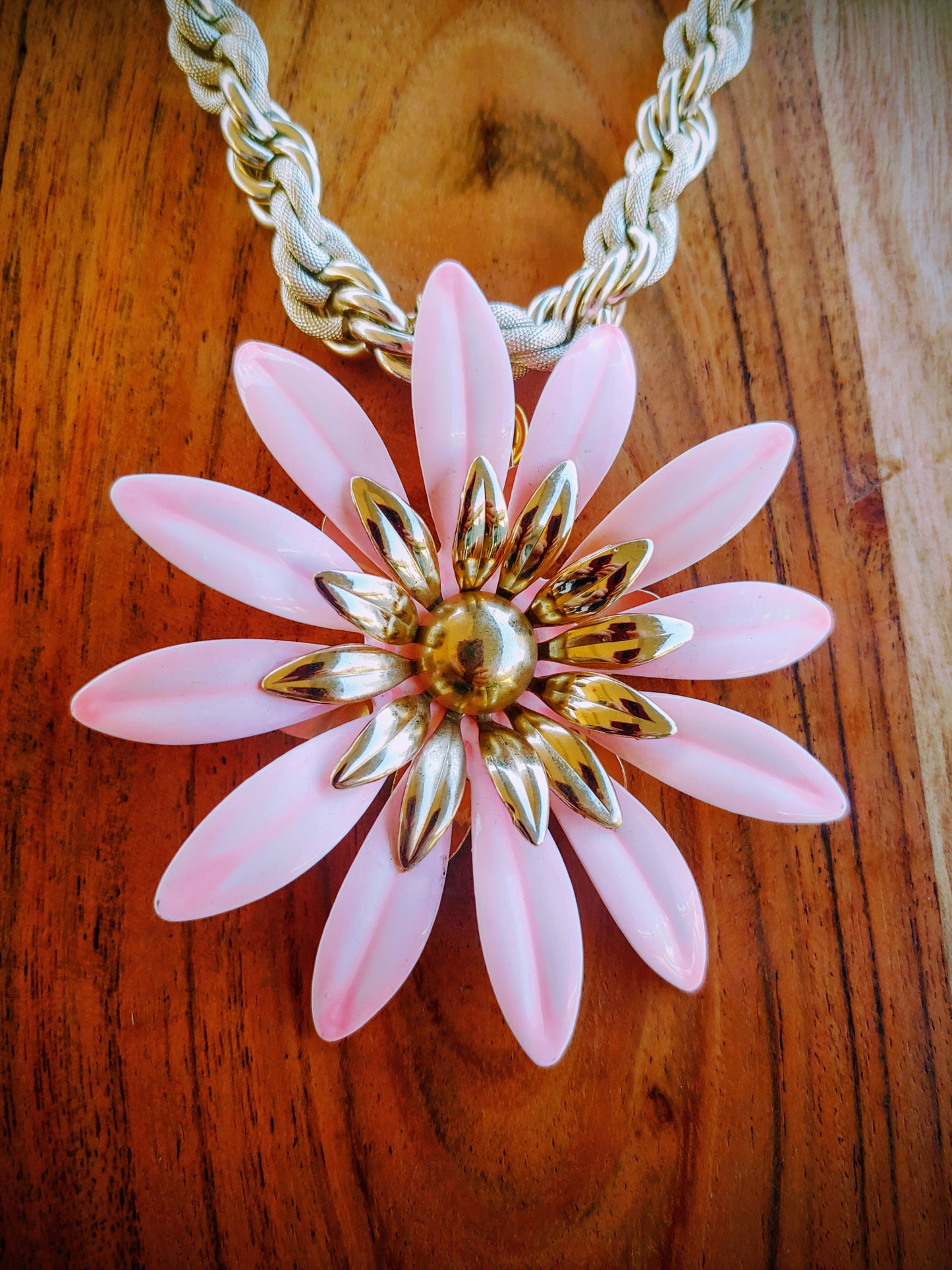 Necklace with a pink flower pendant on a wooden surface