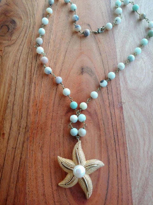 Necklace with starfish pendant and turquoise beads on a wooden surface