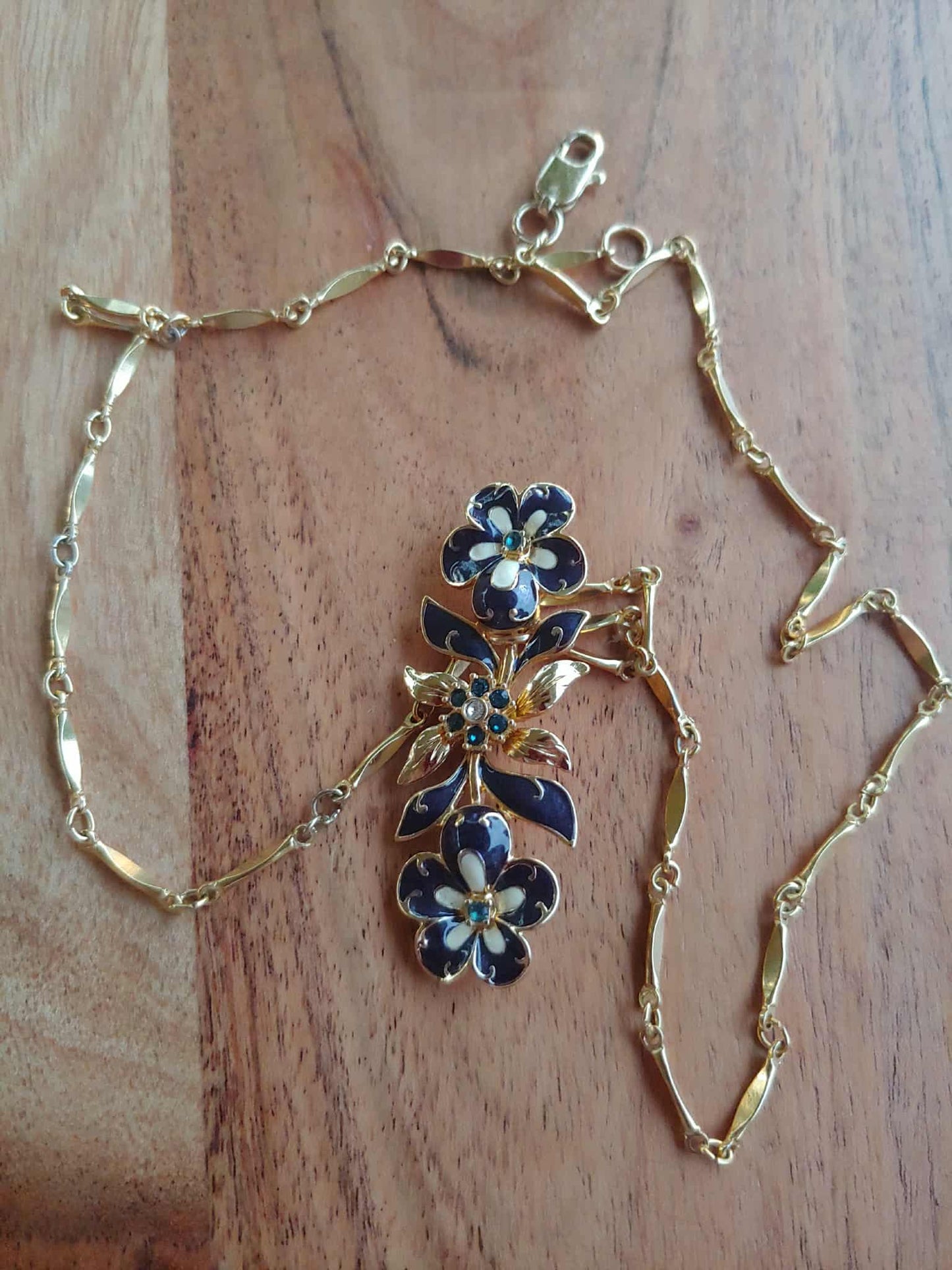 Gold necklace with floral clasp on a wooden surface