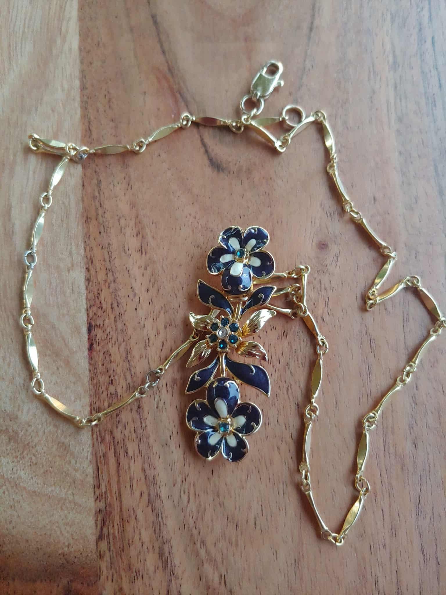 Gold necklace with floral clasp on a wooden surface