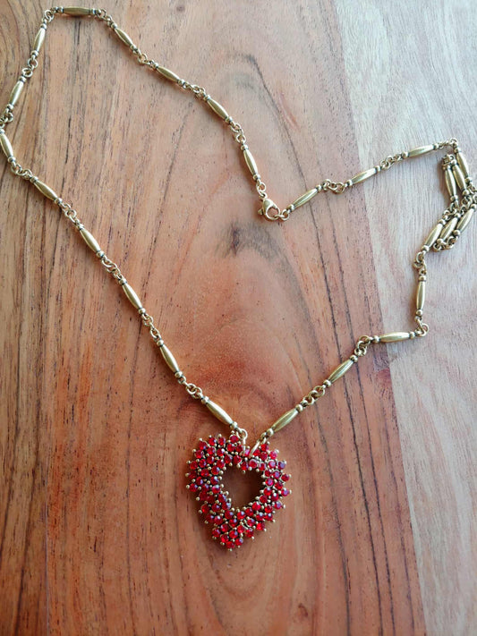 Necklace with a red heart-shaped pendant on a wooden surface