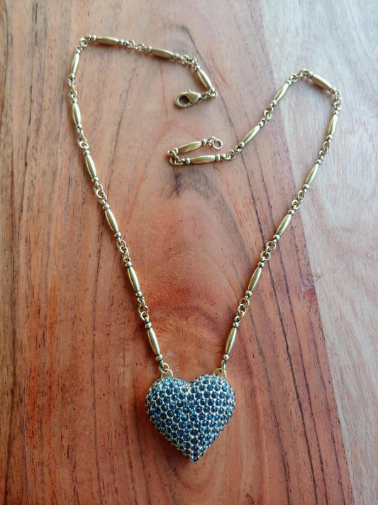 Gold necklace with a blue heart-shaped pendant on a wooden surface