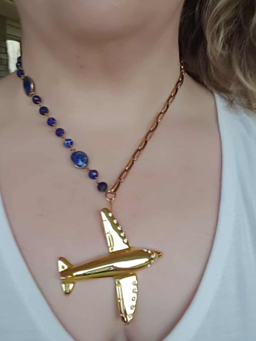Gold airplane pendant necklace on a white shirt