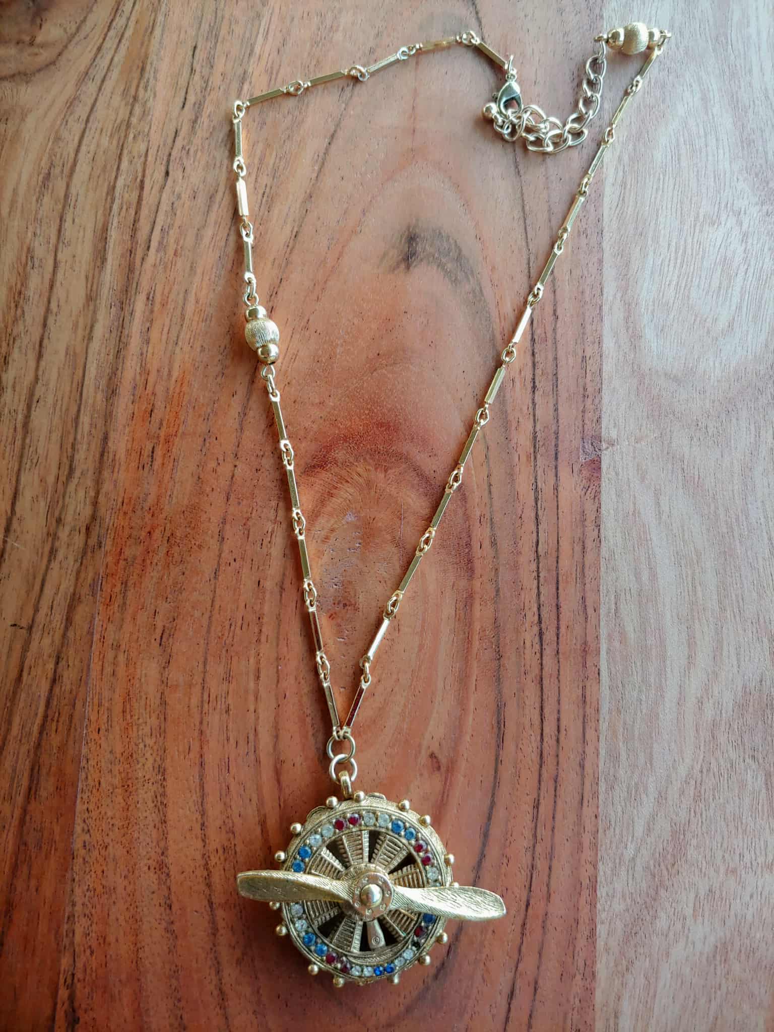 Gold necklace with a decorative pendant on a wooden surface