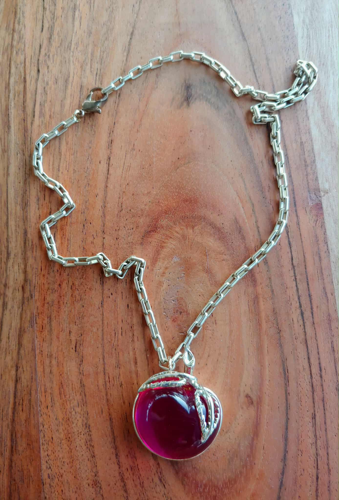 Silver bracelet with a red gemstone on a wooden surface