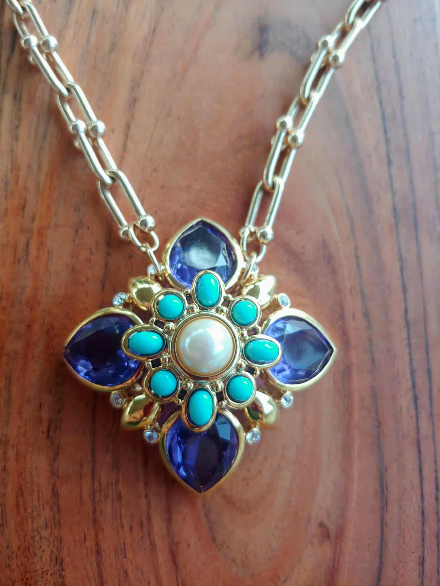 Necklace with a decorative pendant featuring blue and turquoise stones on a wooden surface