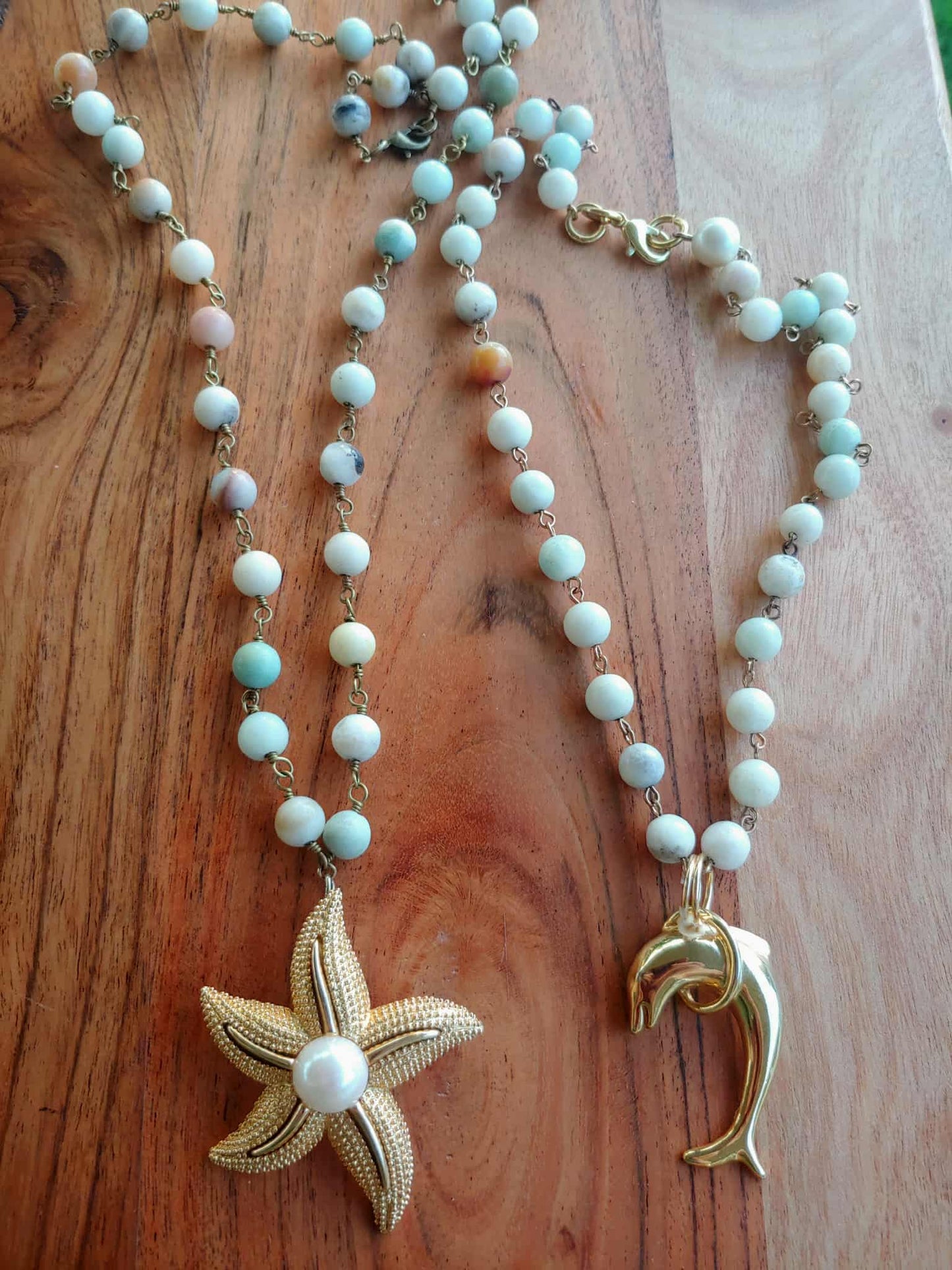 Necklace with starfish and dolphin pendants on a wooden surface