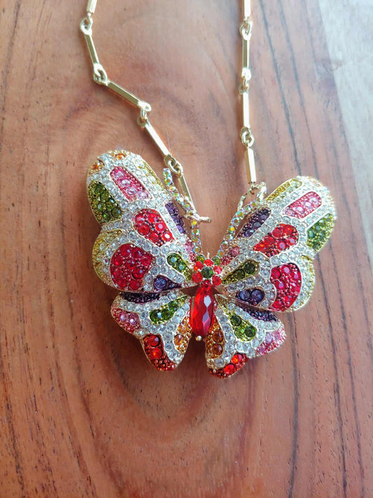 Colorful butterfly-shaped pendant on a chain against a wooden background