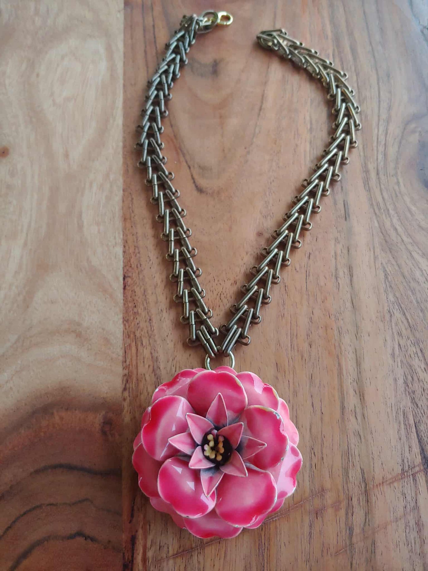 Necklace with a pink flower pendant on a wooden surface