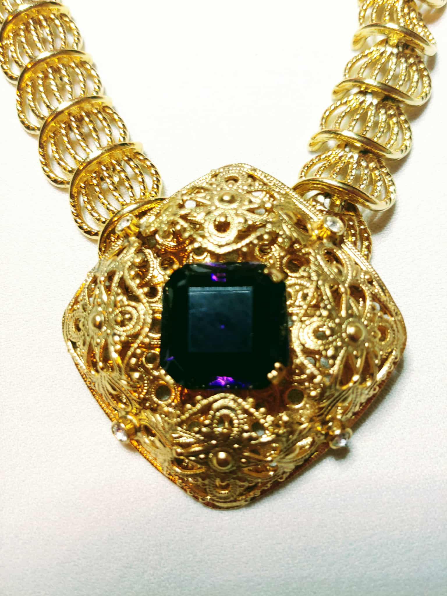Gold necklace with a central gemstone on a white background