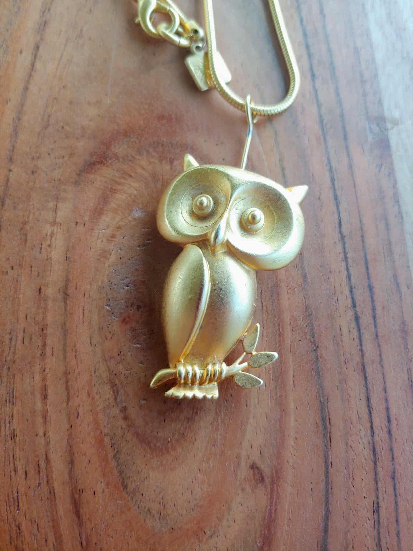 Gold owl-shaped keychain on a wooden surface