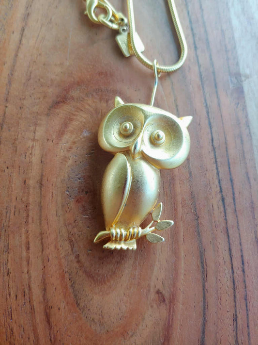 Gold owl-shaped keychain on a wooden surface