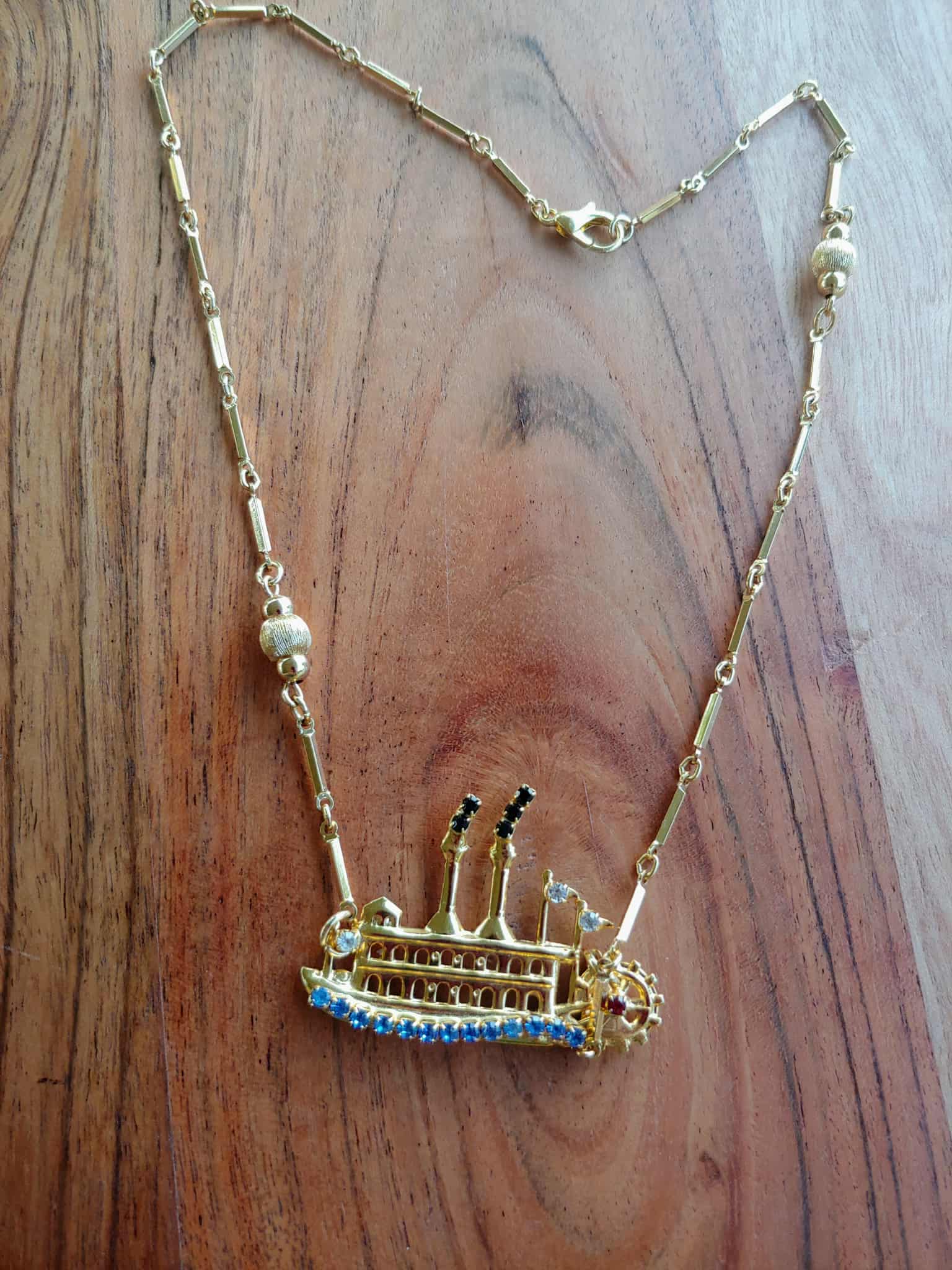 Gold necklace with a detailed pendant on a wooden surface