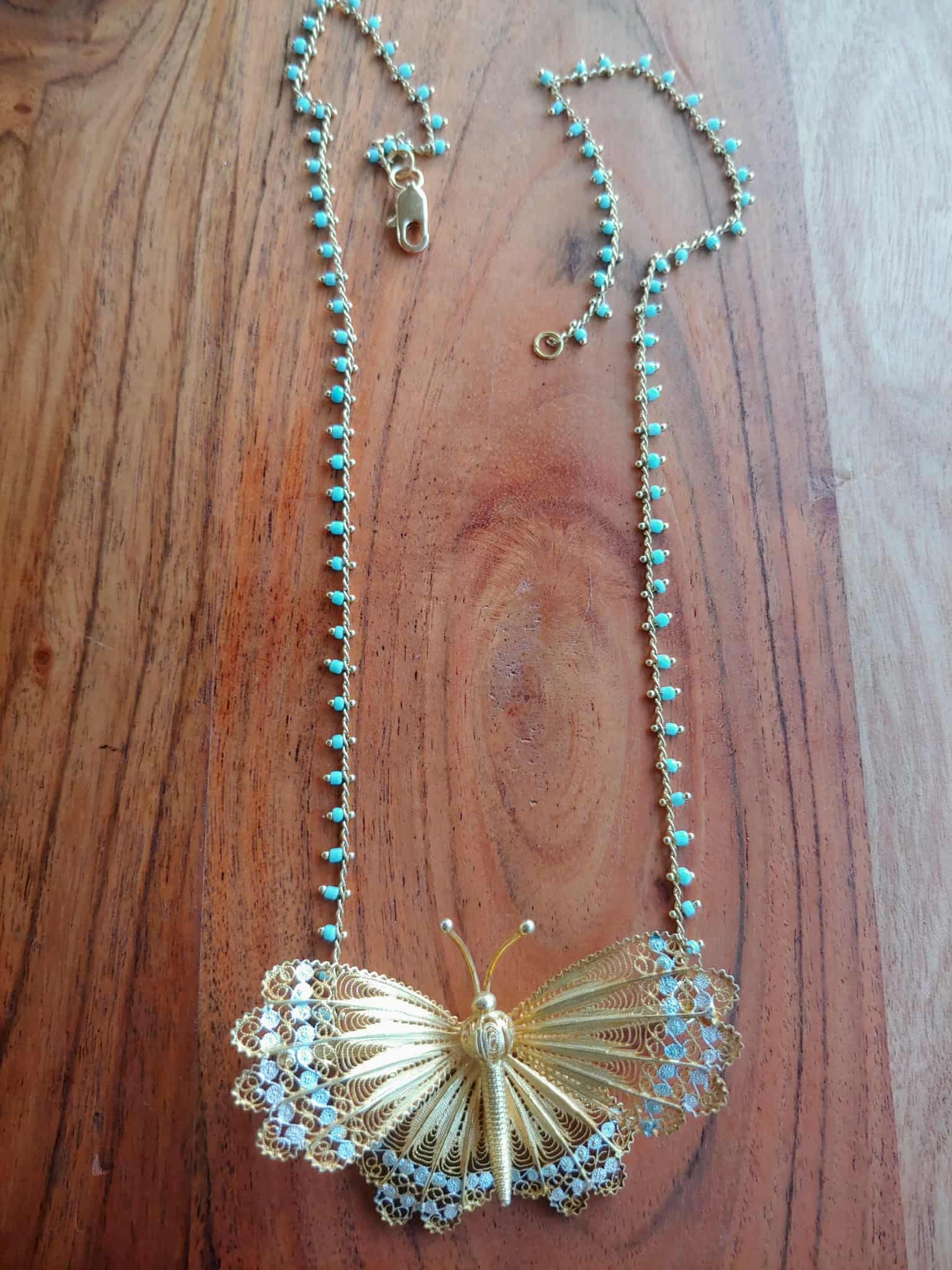 Gold butterfly necklace on a black background