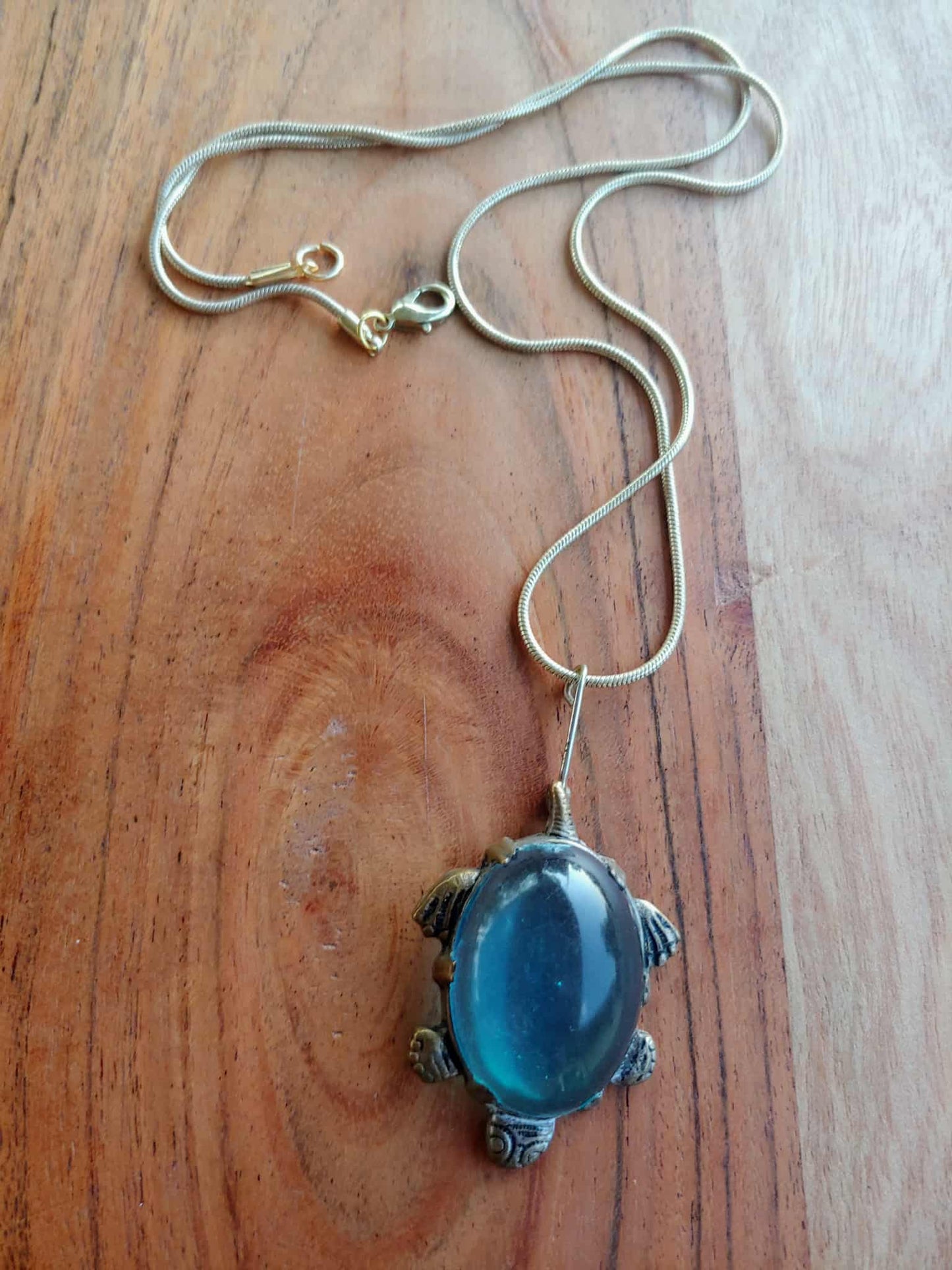 Necklace with a blue pendant on a wooden surface