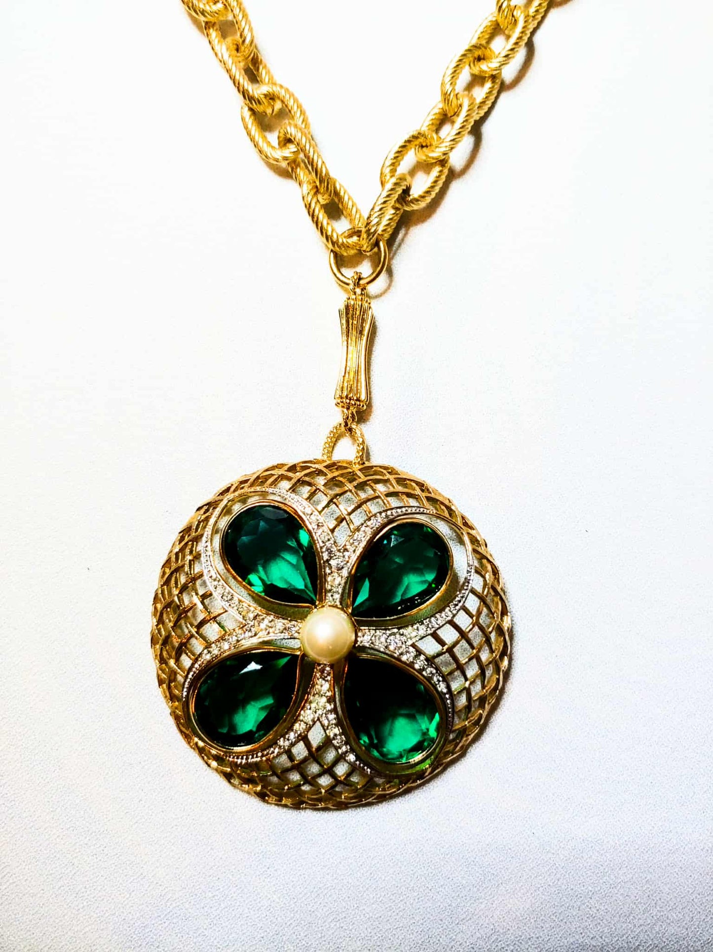 Gold necklace with a green gemstone pendant on a white background