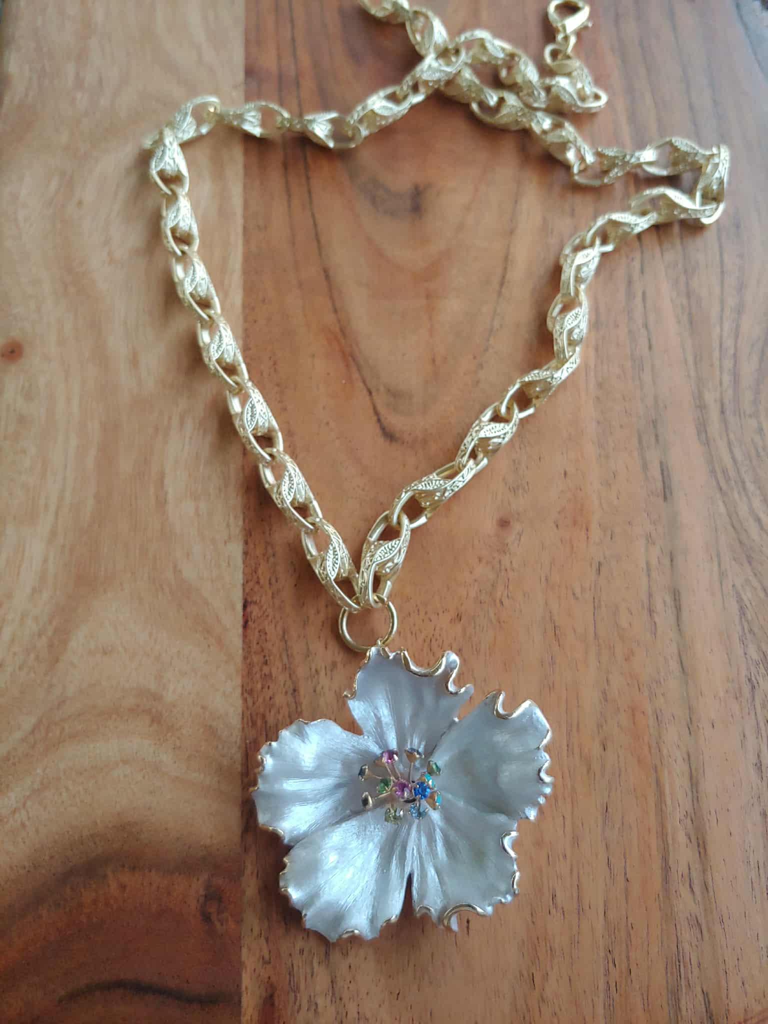 Necklace with a white flower pendant on a wooden surface