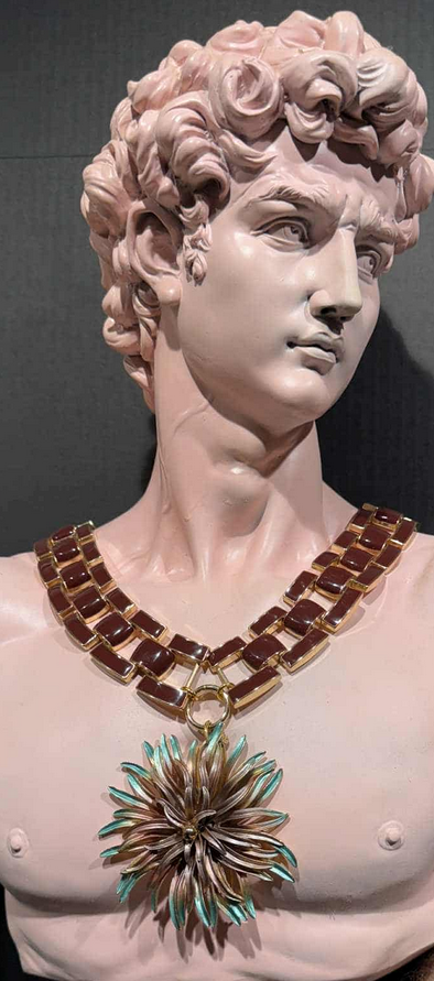 Bust of a classical figure wearing a decorative necklace with a large pendant.