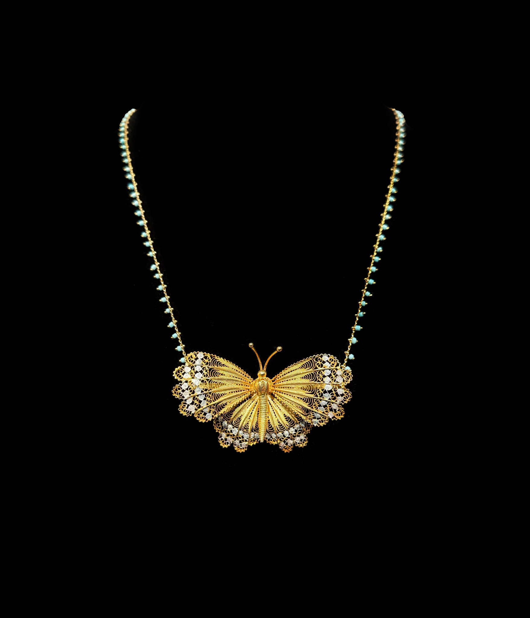 Gold butterfly necklace on a black background