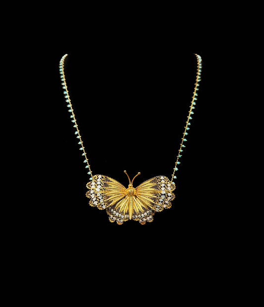 Gold butterfly necklace on a black background