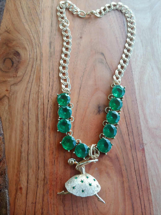 Necklace with green gemstones and a gold charm on a wooden surface