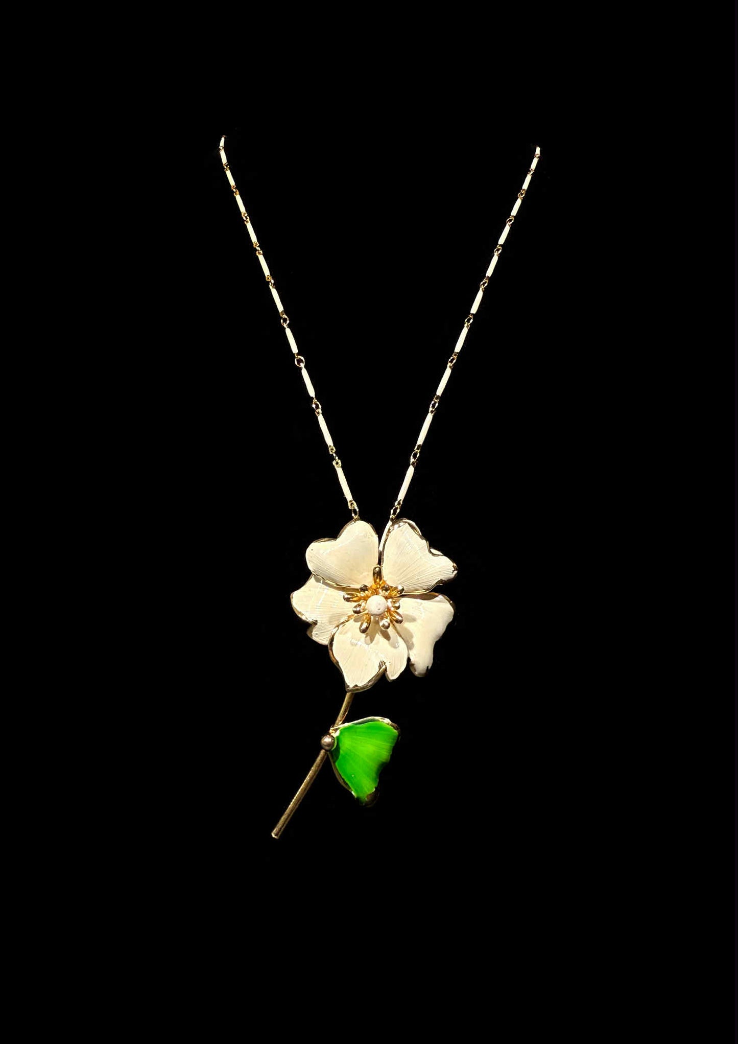 Floral pendant necklace with a green leaf on a black background