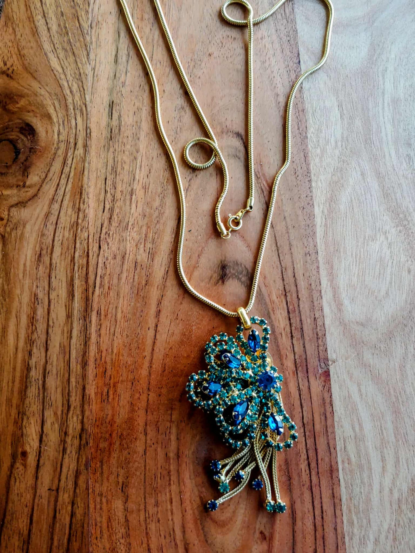 Necklace with a peacock-shaped pendant on a wooden surface