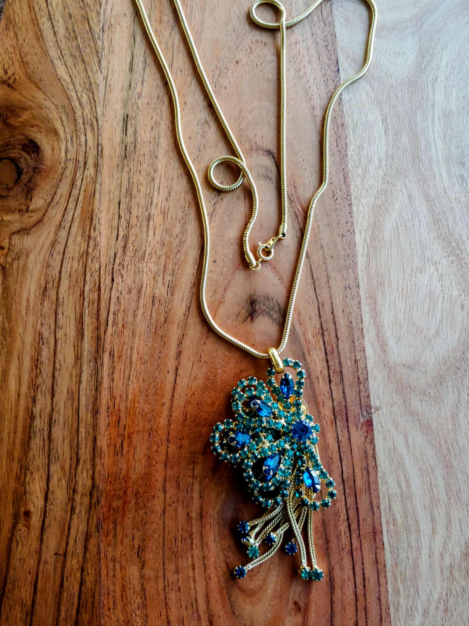 Necklace with a peacock-shaped pendant on a wooden surface