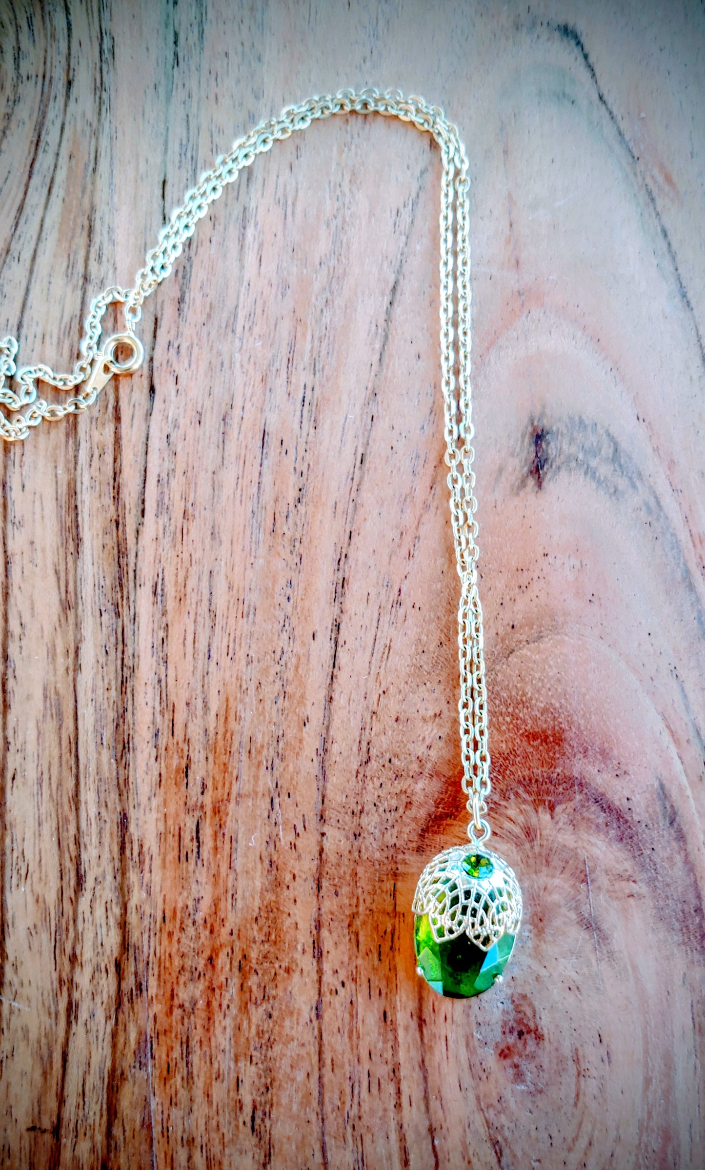 Necklace with a green pendant on a wooden surface