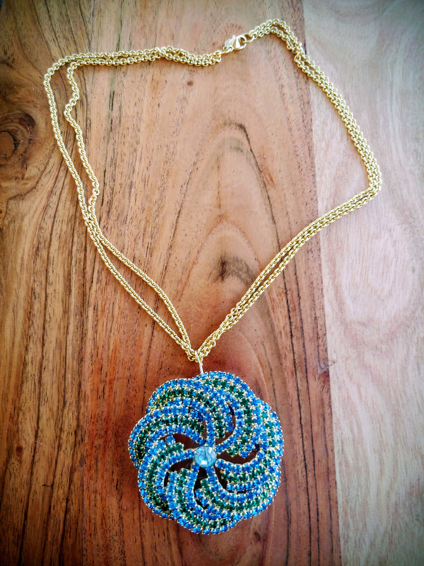 Necklace with a blue and green beaded pendant on a wooden surface