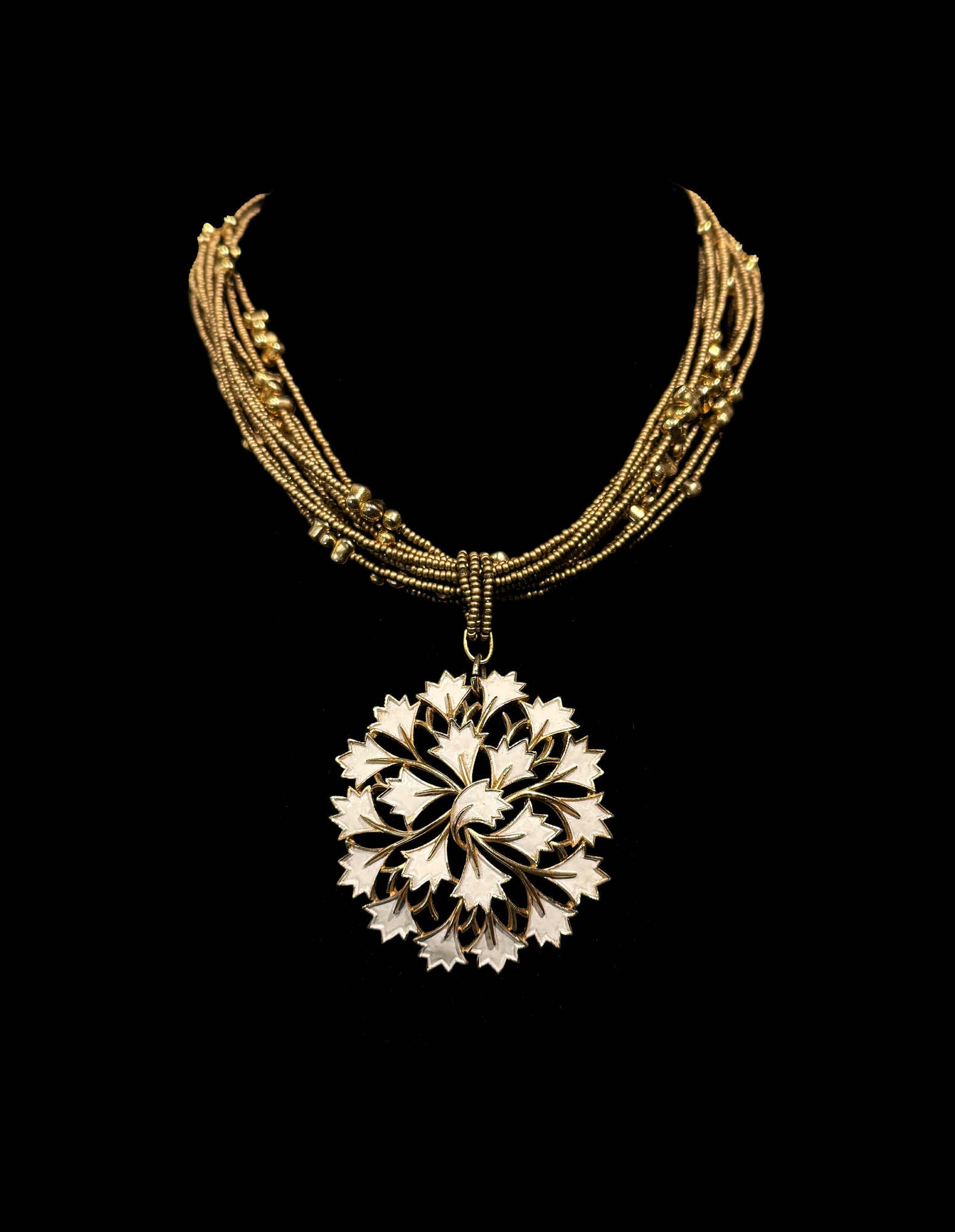 Gold necklace with a detailed pendant on a black background