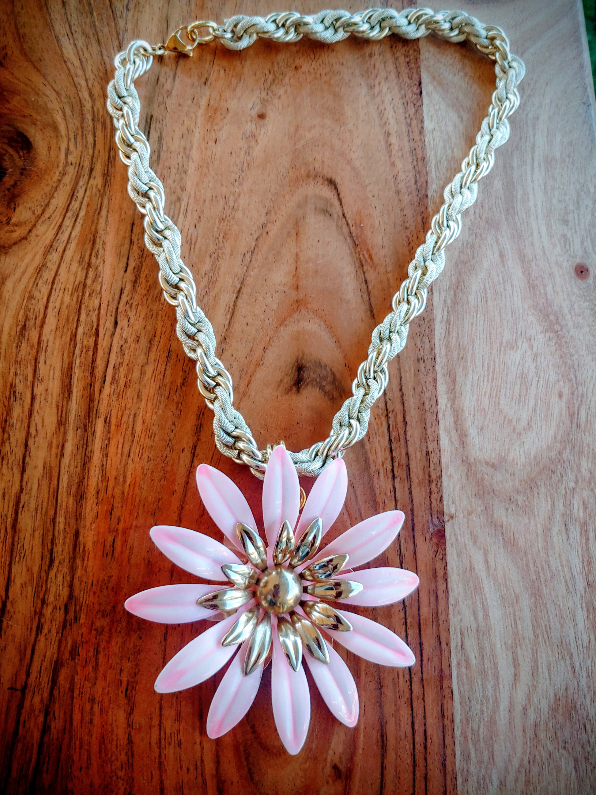 Necklace with a pink flower pendant on a wooden surface