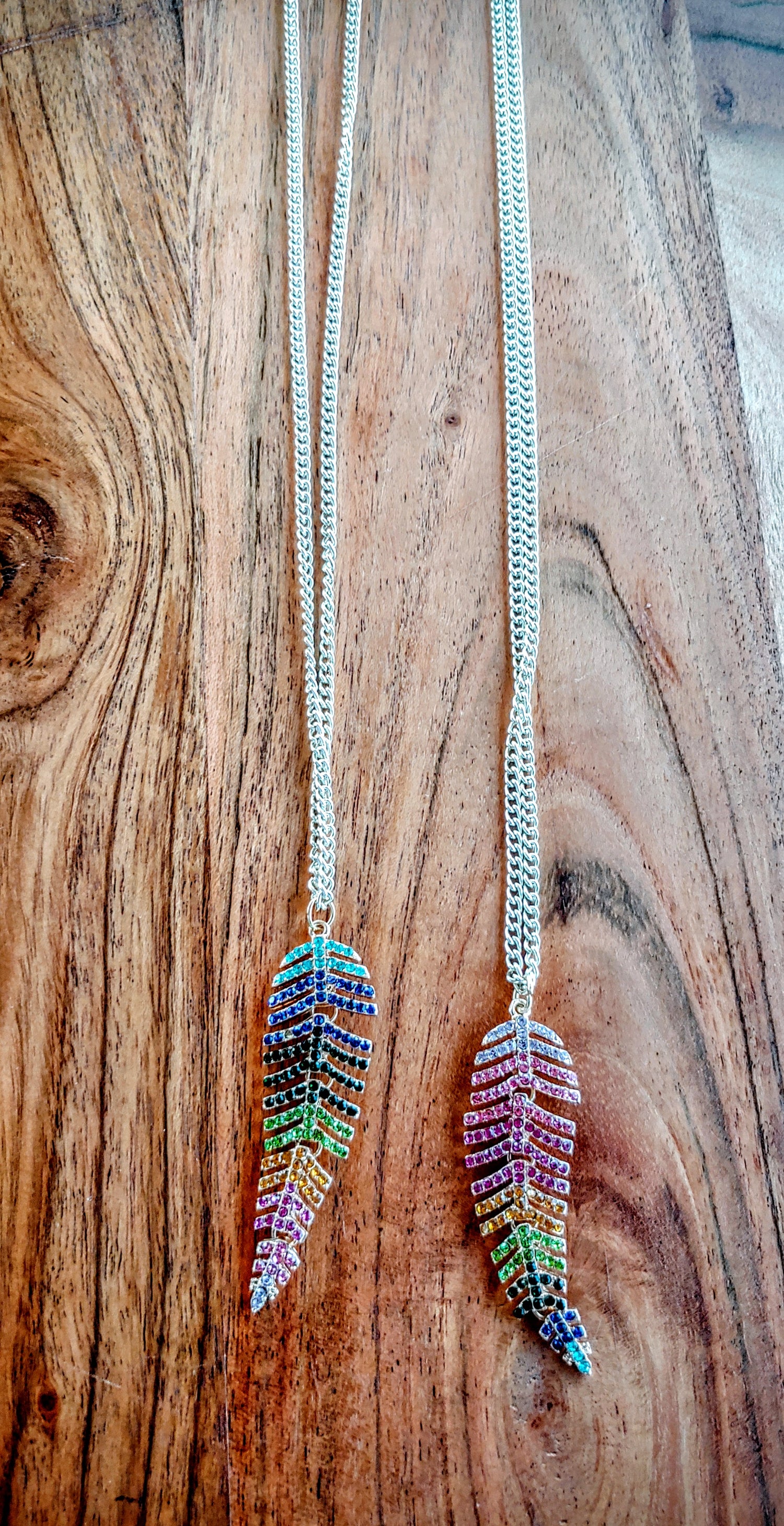 Necklace with feather-shaped pendant on a wooden surface