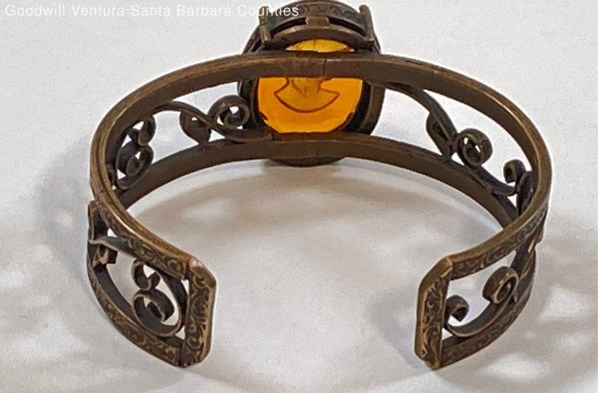 Bronze cuff bracelet with Abackgroundmber glass carving on white 