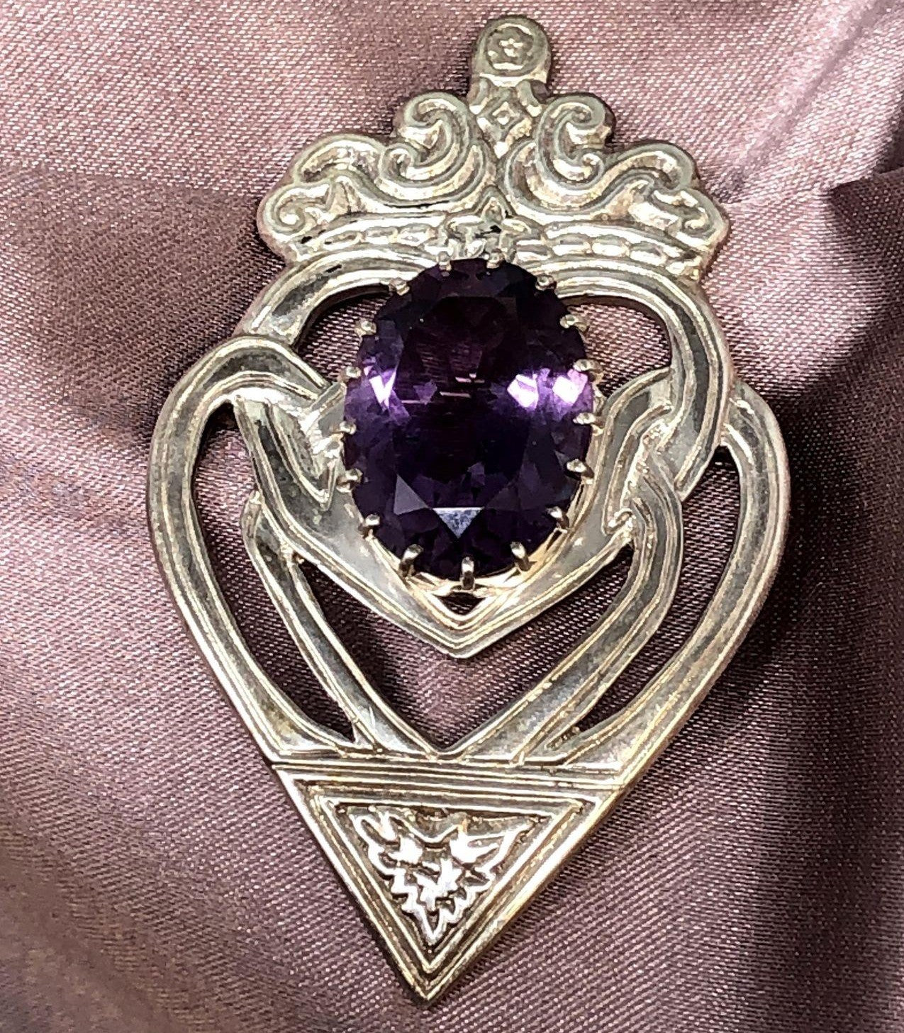 Purple amethyst and sterling silver brooch on pink cloth
