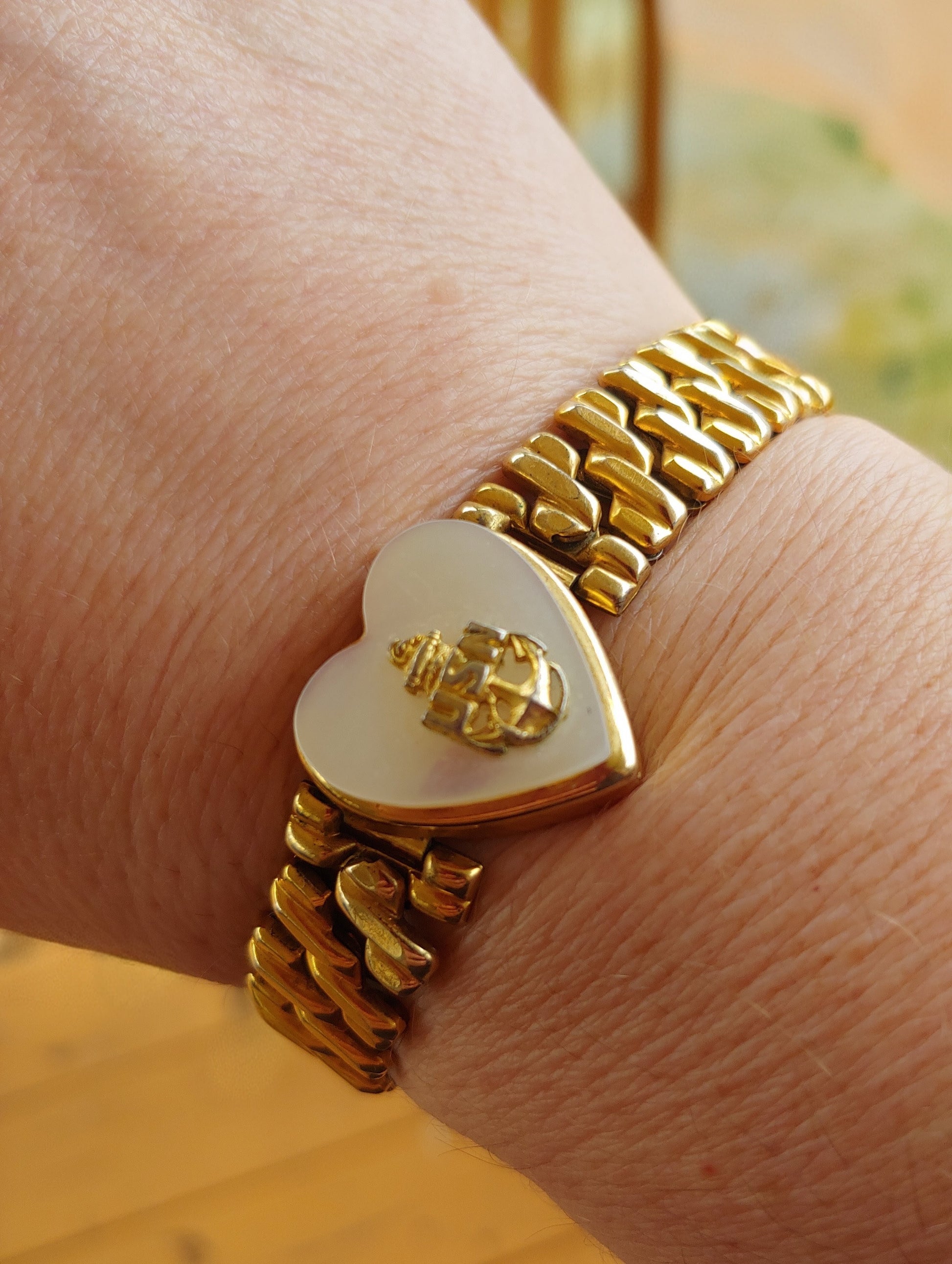 Gold bracelet with a heart-shaped clasp on a wrist
