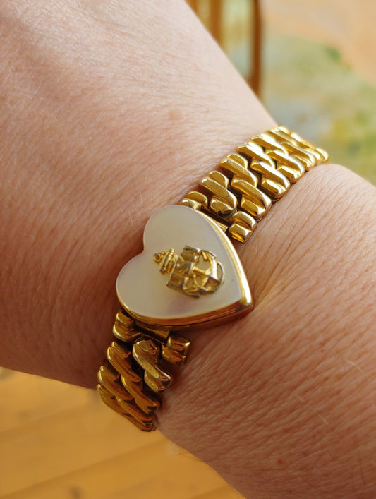 Gold bracelet with a heart-shaped clasp on a wrist