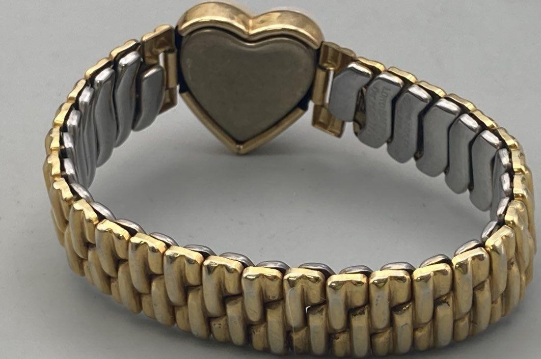 Gold and silver bracelet with a heart-shaped clasp on a gray background