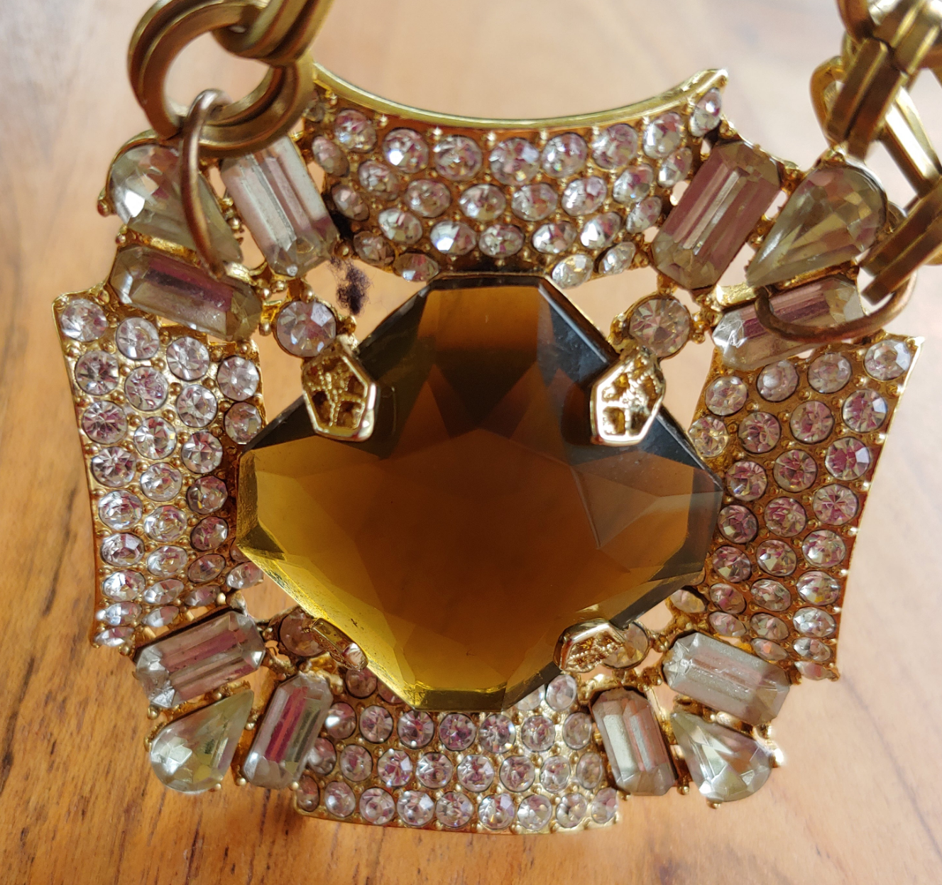 Decorative keychain with gold chain, heart-shaped amber stone, and rhinestones on a wooden surface.