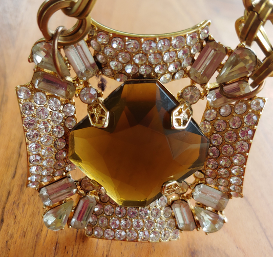 Decorative keychain with gold chain, heart-shaped amber stone, and rhinestones on a wooden surface.